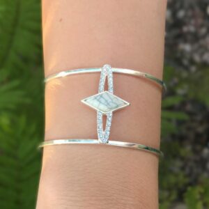 Delicate silver bracelet with a unique centerpiece on a wrist.