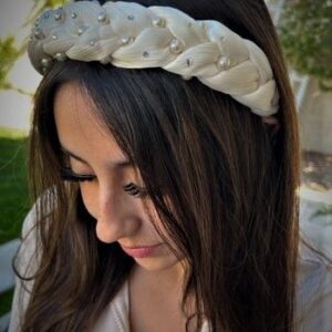 A woman with long dark hair wearing a white headband, looking down with a serene expression.