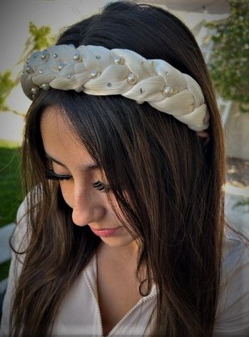 A woman with long dark hair wearing a white headband, looking down with a serene expression.
