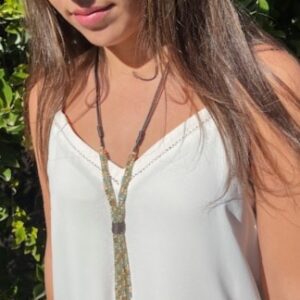 Woman wearing a white top and layered necklaces in sunlight.