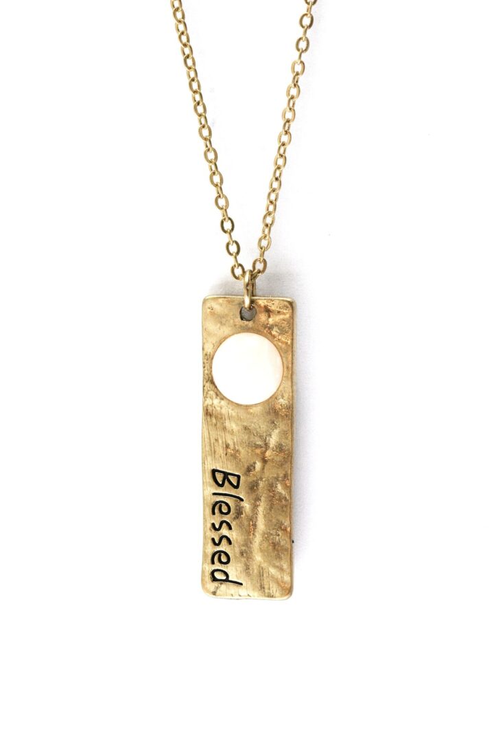 Gold pendant necklace with 'Blessed' engraving and a circular cutout.