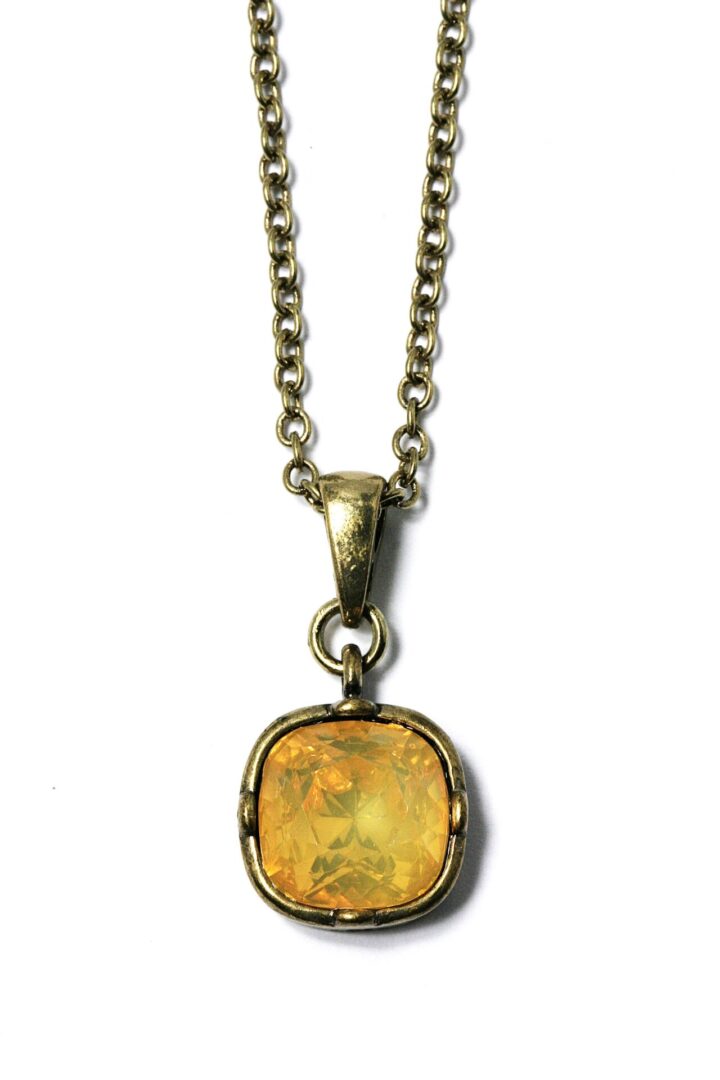 Gold pendant necklace with a yellow gemstone.