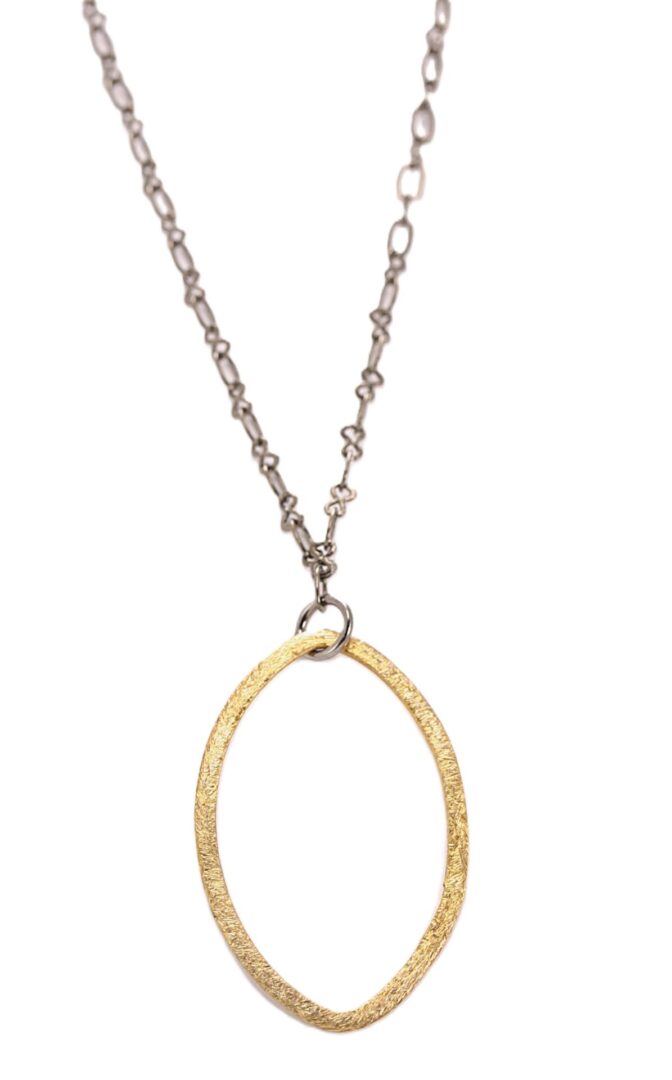 A delicate pendant necklace with a large gold oval charm on a thin silver chain.