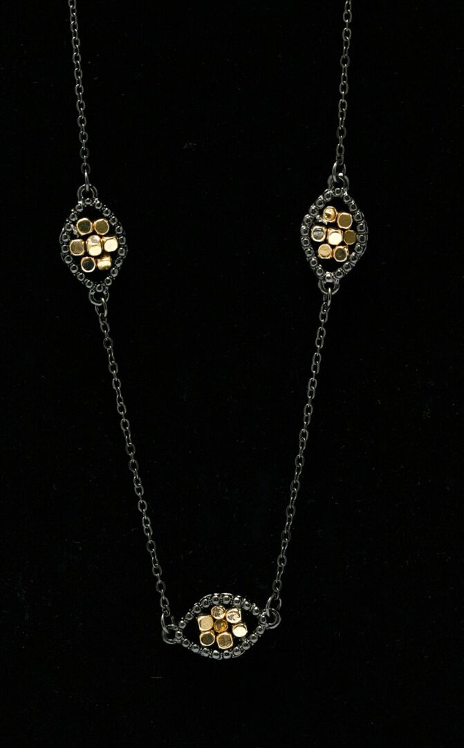 Elegant gold and black pendant necklace with intricate details on a black background.