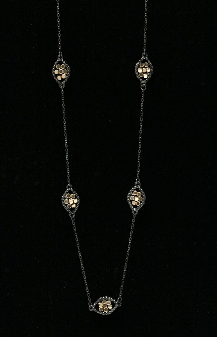 Delicate silver chain necklace with intricate oval-shaped beads.